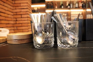 Zarif cam tutacaklardaki parlak kaşıkların şık dizilişi modern yemek atmosferini güzelleştirir.