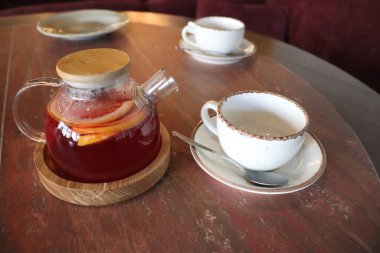 Çok güzel sunulmuş bir bitki çaydanlığı, kırsal ahşap bir masada zarif bir şekilde eşleştirilmiş bir fincan ile.