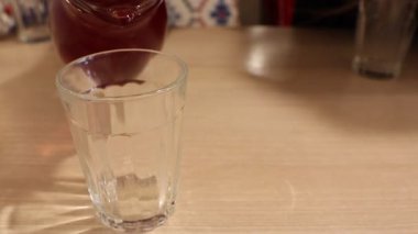 Canlı, renkli bir içecek dikkatlice temiz bir bardağa dökülüyor, hoş ve ferahlatıcı bir deneyim sergiliyor.