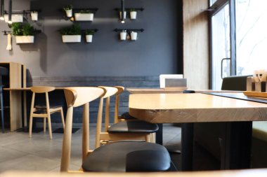 Bu şık ve rahat kafe içi, sıcak bir ortam için güzel ahşap mobilyalar ve yemyeşil bir yer.