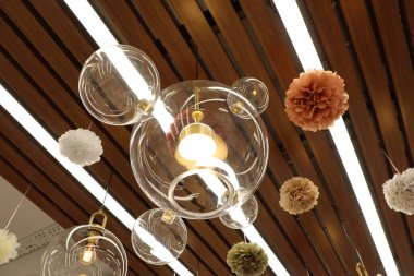 Benzersiz kolye ışıkları şık kağıt dekorlarıyla birleşince modern iç mekanların estetiğini önemli ölçüde geliştiriyor.