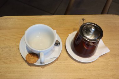 Samimi bir çay takımı, zarif bir çaydanlık ve kırsal bir ahşap masada güzelce yerleştirilmiş bir kurabiye.