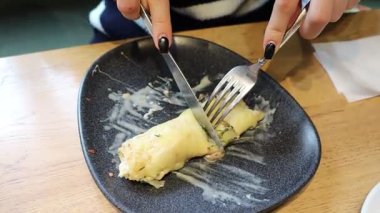 Lezzetli bir yemeğin tadını çıkarmak ve tadını çıkarmak, güzel bir tabakta ustalıkla kesilmiş çatal ve bıçakla.