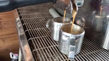 Sıcak, zengin bir espresso makinesinin parlak fincanlarına harika bir şekilde dökülen yakın çekim görüntüsü.