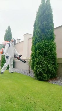 Becerikli bir haşere kontrol uzmanı düzenli olarak bakımlı ve güzel bir bahçe alanında tedavi uyguluyor.