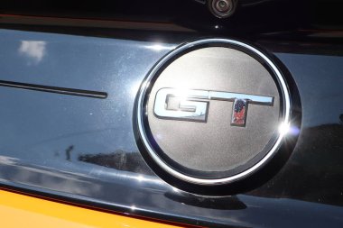 Bir GT ambleminin yakın plan görüntüsü, zarif tasarımı ve belirgin otomotiv markalaşma özellikleri sergileniyor.