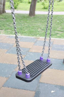 Yeşillik bir park arka planına karşı canlı bir oyun alanı salıncağı, çocuklar için ideal bir oyun ve eğlence.