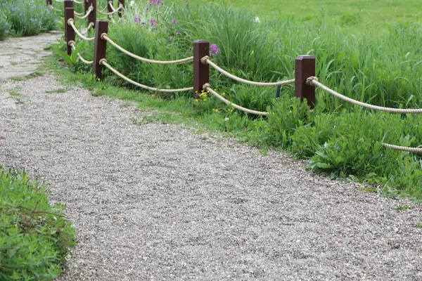 Yeşil ve ahşap direklerle kaplı sakin bir çakıl yolu huzurlu doğa yürüyüşleri ve keşifleri için idealdir.