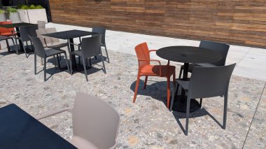 Canlı bir atmosfer için gösterişli masalar ve renkli sandalyelerin yer aldığı çağdaş açık hava yemek alanı.