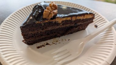 Bu nefis çikolatalı pasta diliminin tadını çıkarın. Güzelce katlanmış ve çıtır çıtır fındıklarla kaplı.
