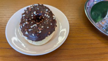 Beyaz bir tabağa rengarenk şekerlemeler serpiştirilmiş cazip bir çikolatalı çörek. Her yerdeki tatlı severler için bir zevk.