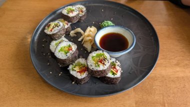 Lezzetli suşi tabağının tadını çıkarın. Taze ekmekler, lezzetli soya sosu ve renkli süslemeler harika bir deneyim için.