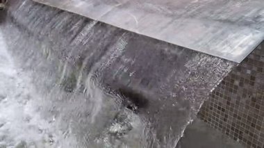 Pürüzsüz, paslanmaz çelik bir kenarda çağlayan suyun büyüleyici görüntüsü sakin bir ortam yaratıyor..