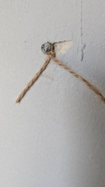 Bu, bir çivinin yardımıyla iç duvara sıkıca bağlanmış bükülmüş bir halatın yakın çekim görüntüsü.