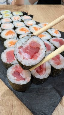 Taze ton balığı ve somondan oluşan çeşitli suşi rulolarının canlı ve renkli bir görüntüsü, yemek severler için mükemmel.