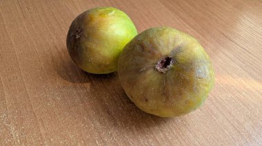 İki olgun yeşil meyve kırsal ahşap bir yüzeyde doğal bir estetik sergileniyor.