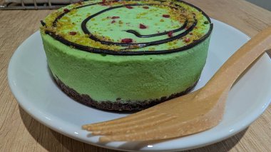Zengin çikolata tabanlı ve dekoratif kıvrımlı canlı yeşil bir cheesecake, tatlı aşıkları için mükemmel..