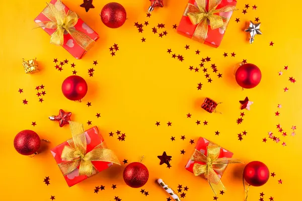 あなたの挨拶のための空の円が付いている黄色い背景の黄金のリボン弓が付いている赤いペーパーで包まれるギフト用の箱が付いているクリスマスおよび新年の構成は モックアップします — ストック写真