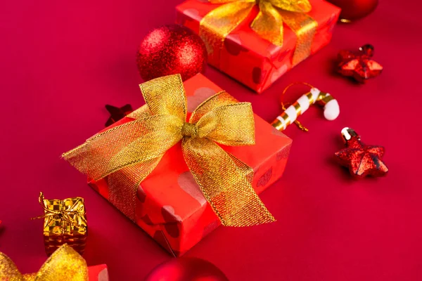お祝いのメッセージのための部屋が付いている赤い背景の金のリボン弓が付いている赤いペーパーで包まれる休日のギフト用の箱 クリスマスの背景 挨拶カード モックアップ — ストック写真