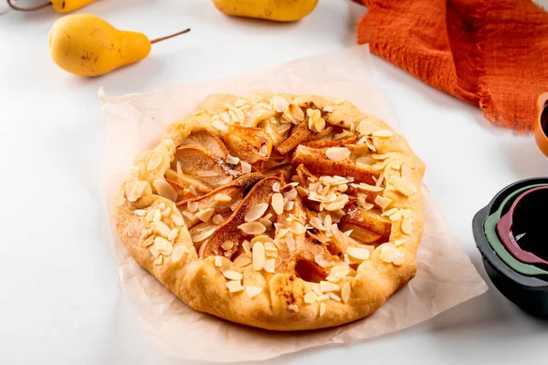 Baked galette or open pie with pear, cinnamon and almond flakes on the table