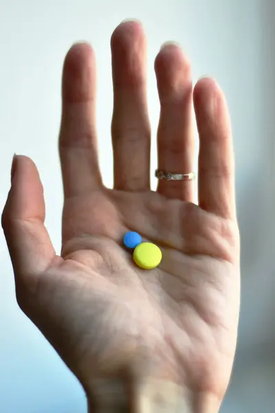 黄色と青の錠剤を保持手 — ストック写真
