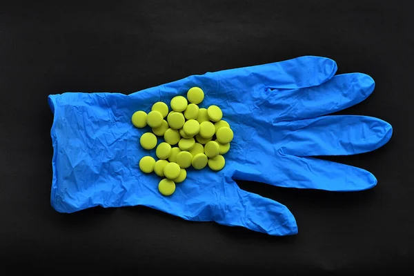 黄色い丸薬は青い手袋の上にある — ストック写真