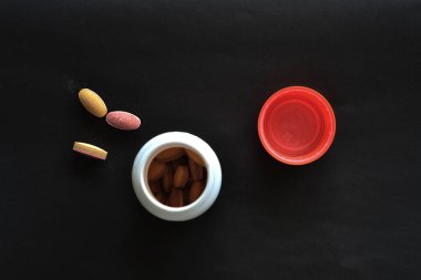 Siyah arka planda vitaminli bir kavanoz var.