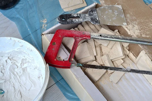 Repair tools, decorative tiles, saw and spatula.