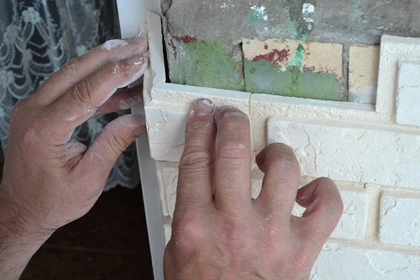 A man puts a beige decorative tile on the wall