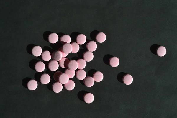 ピンクの錠剤は黒い背景にあります — ストック写真