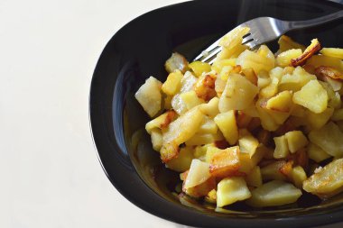 Siyah bir tabakta beyaz bir masada kızarmış patates.