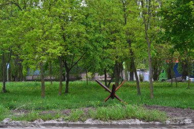 Bir tanksavar parktaki yeşil ağaçların arasında duruyor.