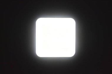 Kare bir lamba siyah tavanda parlıyor