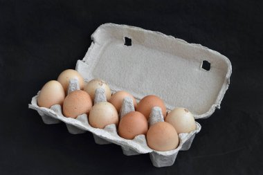 10 yumurtalı bir kutu siyah bir arkaplanda yatıyor.