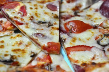 Dilimlenmiş lezzetli pizza tabakta yatıyor.