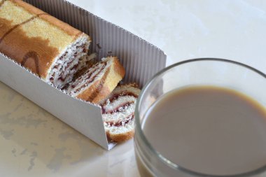 Masanın üzerinde tatlı ekmek ve kahve var.