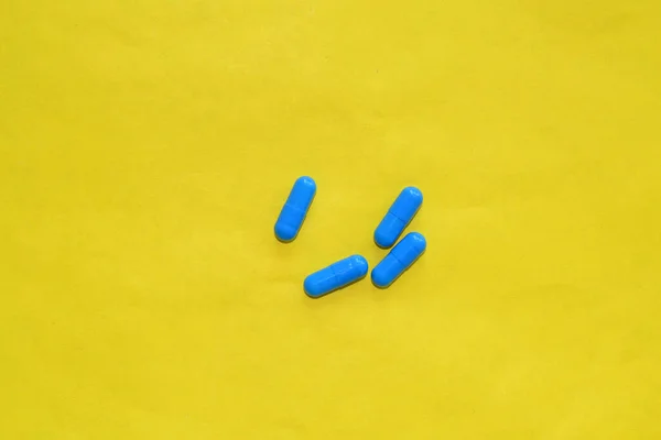 青い錠剤は黄色の背景にあります — ストック写真