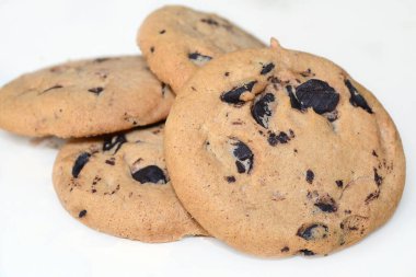 Masanın üzerinde çikolata damlaları olan beyaz kurabiyeler.