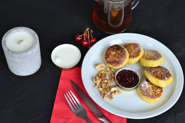 stock image there is a candle and tea near a plate of cheese pancakes