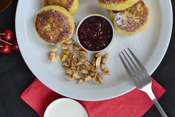 stock image next to cheese pancakes there is jam and nuts