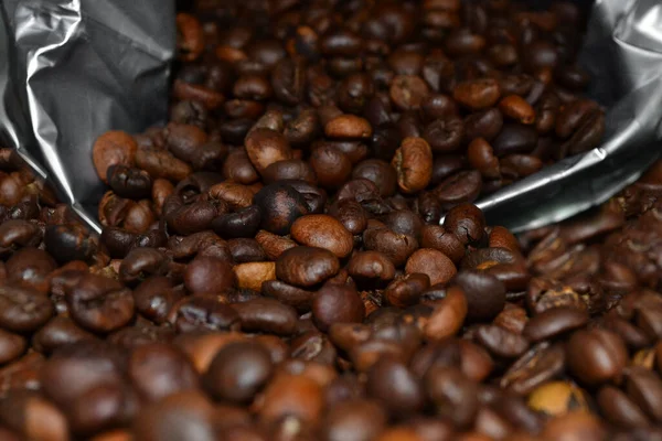 Kaffeebohnen Aus Einer Packung Liegen Auf Einem Schwarzen Tisch Verstreut — Stockfoto