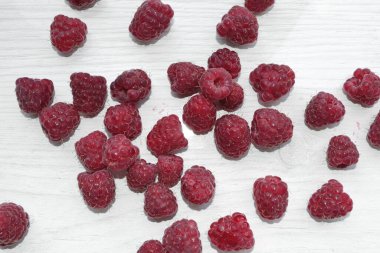 Beyaz bir masaya serpilmiş pembe ahududular.