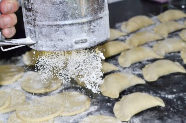 Bir kadın hamurun üzerine un serper.