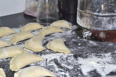 Bir kadın hamur işini metal bir bardaktan un serpiyor.