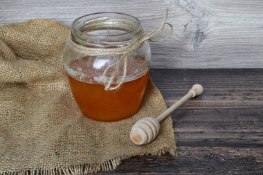 Bir kavanoz bal karanlık bir masada duruyor.