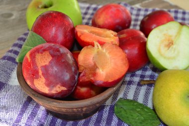 Bir tabakta erik ve havlunun üstünde elma.