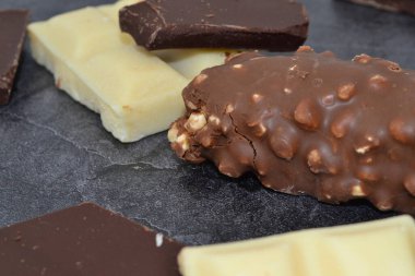 çeşitli çikolatalar siyah bir masanın üzerinde yatıyor.