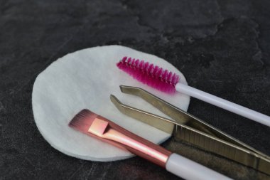 Masanın üzerindeki pamuk bloknotta kaş aletleri var.