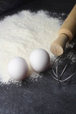 Bir merdane ve iki yumurta siyah bir masada yatıyor.