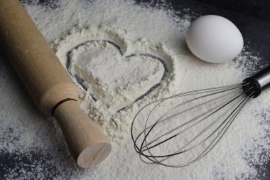 Un üzerine bir kalp çizilir, ve yanında bir merdane, bir yumurta ve bir çırpı.